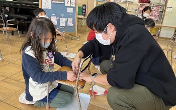 写真:先生と一緒に折り紙をする子ども