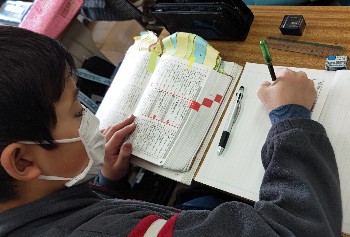写真:辞書を引いてノートを取る生徒