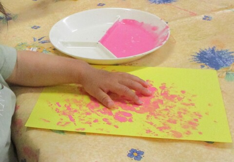 絵の具を指に付け、画用紙に指でお絵描きしている子ども