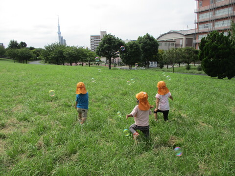 飛んできたしゃぼん玉を追いかけている子どもたち