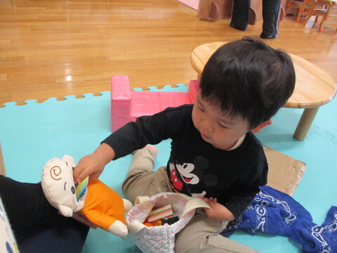 赤ちゃん人形におもちゃの魚を食べさせている子ども