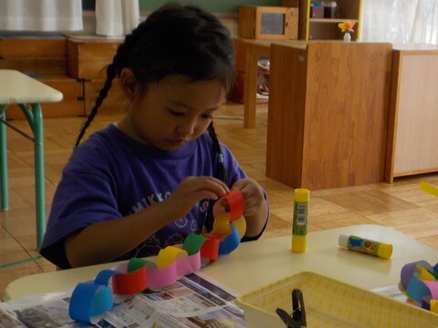 輪飾りを作っている子どもの写真