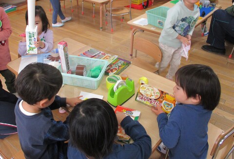 水性ペンやビニールテープなど様々な材料を使って空き箱制作をする子どもたち。