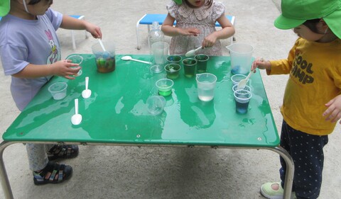 テーブルの上で色水遊びをする子どもたち